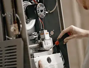 Furnace repair technician inspecting internal components and wiring in Kissimmee, FL