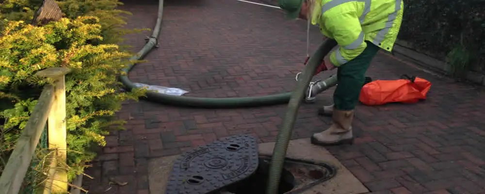 Septic tank cleaning technician servicing a septic tank with a vacuum hose in Kissimmee, FL
