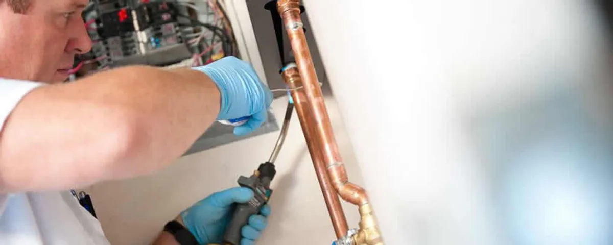 Water heater repair technician testing copper pipe connections and controls in Kissimmee, FL